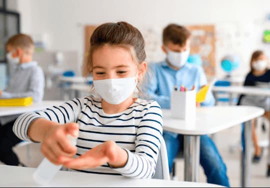 una bambina si disinfetta le mani a scuola