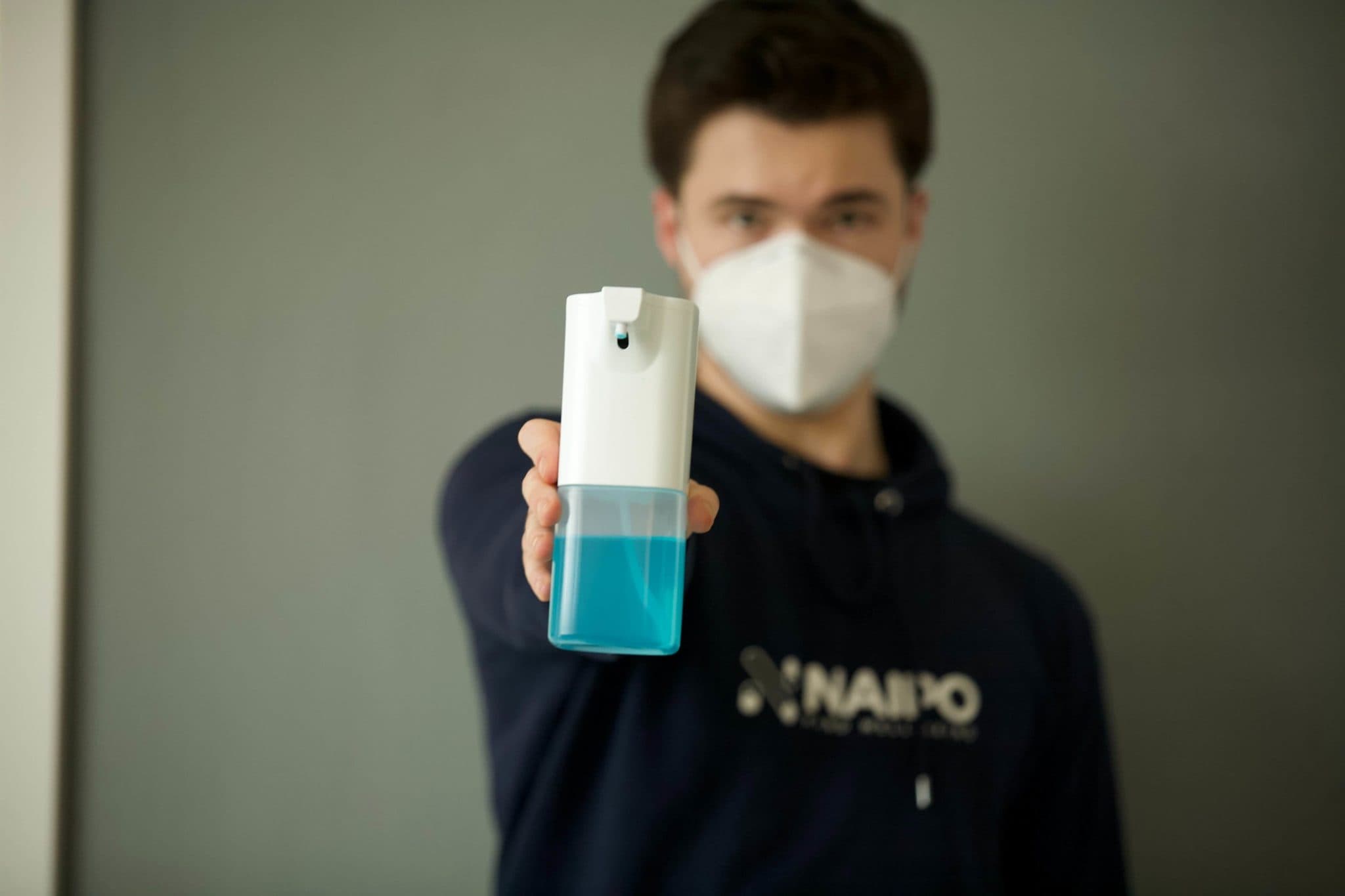 un ragazzo mostra un igienizzante blu